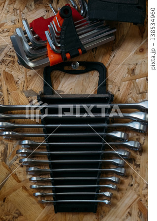 Workshop tools. Spanner set. Hex key chrome professional combination wrenches arranged by size in black holder rack on wooden wall. 138534960