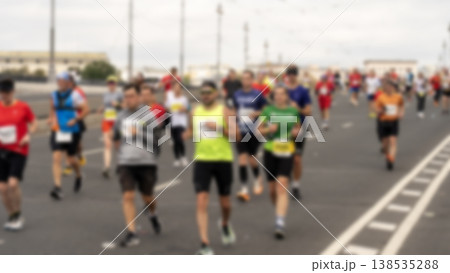 Blurry runners sprint down a wide urban road 138535288