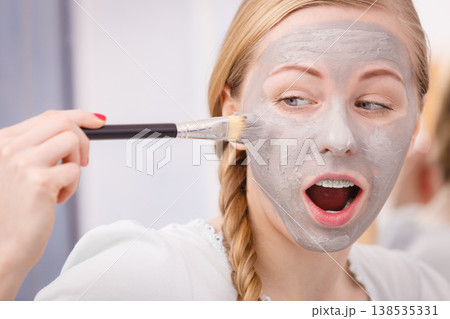 Woman applying with brush clay mud mask to her face 138535331