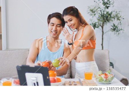 A happy couple prepares fresh vegetables, laughing and enjoying cooking a healthy meal together. A happy couple prepares fresh vegetables, laughing and enjoying cooking a healthy meal together. 138535477