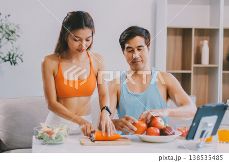 A happy couple prepares fresh vegetables, laughing and enjoying cooking a healthy meal together. 138535485