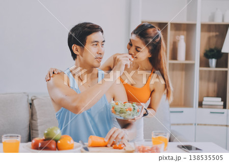 A happy couple prepares fresh vegetables, laughing and enjoying cooking a healthy meal together. A happy couple prepares fresh vegetables, laughing and enjoying cooking a healthy meal together. 138535505