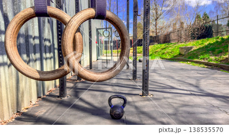Wooden gymnastic rings and kettlebell in outdoor functional fitness gym with copyspace and strength equipment Wooden gymnastic rings and kettlebell in outdoor functional fitness gym with copyspace and strength equipment 138535570