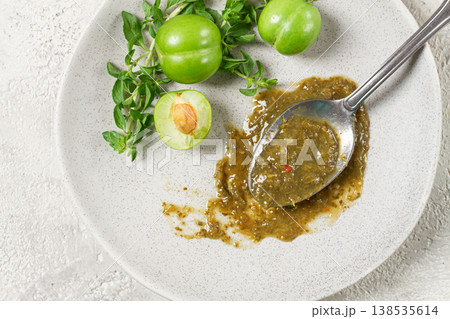 a spoon with tkemali sauce, on a plate, with cherry plum and mint, top view, no people, a spoon with tkemali sauce, on a plate, with cherry plum and mint, top view, no people, 138535614
