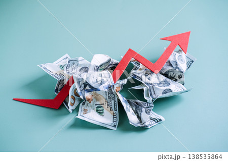 Red arrow trends upward through pile of crumpled dollar bills on blue background. Global inflation rates, rising consumer prices, economic growth trend. 138535864