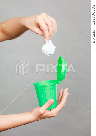 Woman putting paper into small trash can Woman putting paper into small trash can 138536333