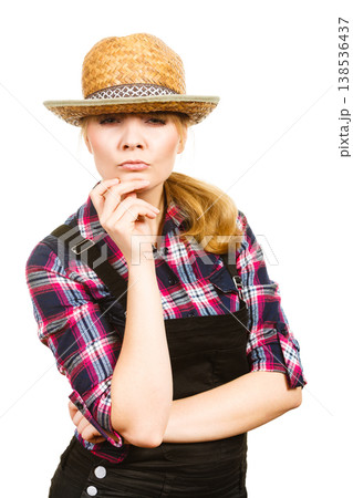 Thinking woman wearing sun hat and dungarees Thinking woman wearing sun hat and dungarees 138536437