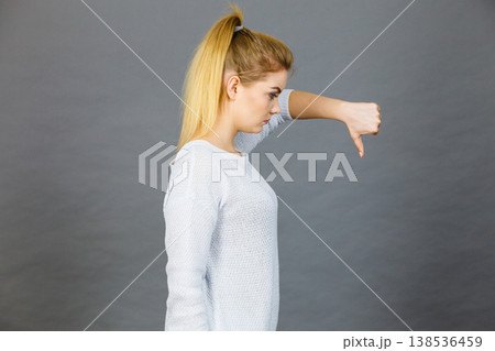 Sad woman showing thumb down gesture 138536459
