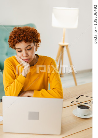 Sleepy sad African American woman sitting at table with laptop. Tired overworked girl lazy to work. Student businesswoman relaxing bored in home office after work on laptop computer 138536492