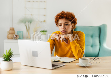 Sleepy sad African American woman sitting at table with laptop. Tired overworked girl lazy to work. Student businesswoman relaxing bored in home office after work on laptop computer Sleepy sad African American woman sitting at table with laptop. Tired overworked girl lazy to work. Student businesswoman relaxing bored in home office after work on laptop computer 138536499