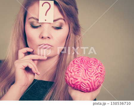 Woman thinking and holding fake brain 138536710
