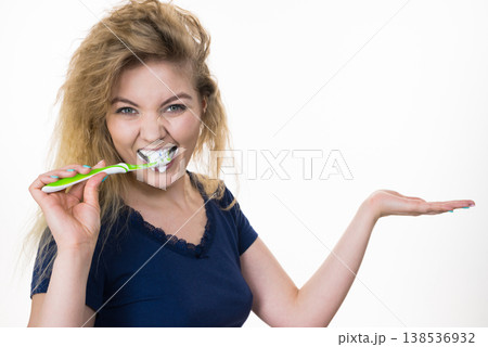 Woman brushing teeth holds open hand Woman brushing teeth holds open hand 138536932