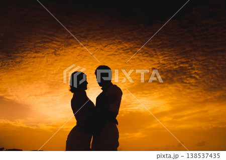 Romantic couple silhouette against dramatic orange sunset sky Romantic couple silhouette against dramatic orange sunset sky 138537435