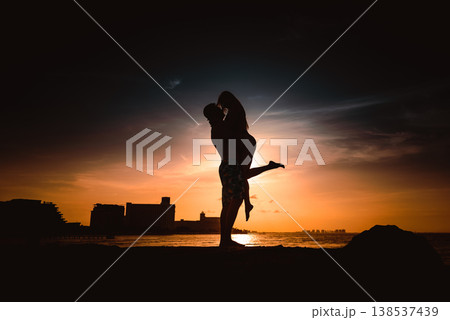Romantic couple silhouette embracing at golden sunset beach Romantic couple silhouette embracing at golden sunset beach 138537439