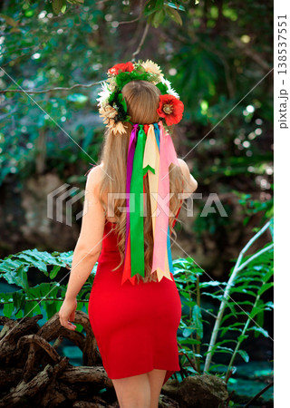 Girl wearing floral crown with colorful ribbons in forest 138537551