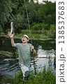Man with fishing rod near the lake fishing at summer. Fisherman catch a fish. Man wearing khaki clothes and a cap. 138537683