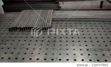 Steel rectangular tubes on a perforated welding table in a metal workshop Steel rectangular tubes on a perforated welding table in a metal workshop 138537942