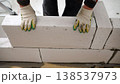 Construction worker in gloves placing a large aerated concrete block while building a wall at a construction site. 138537973