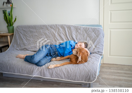 Unconditional love of dog. Relaxed woman gently hug dog on sofa. Animal adoption for lonely female 138538110