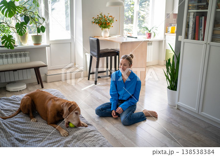 Relaxed mature woman pet owner resting and playing games at home on weekend with beloved dog. Relaxed mature woman pet owner resting and playing games at home on weekend with beloved dog. 138538384