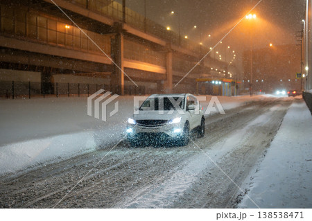 Heavy snowfall and blizzard in city, car driving through roads covered with snow and ice. Heavy snowfall and blizzard in city, car driving through roads covered with snow and ice. 138538471