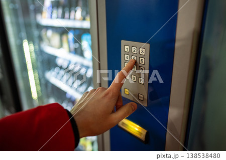 Man customer buying cold drink from automatic vending machine in city, pressing buttons on keypad. Man customer buying cold drink from automatic vending machine in city, pressing buttons on keypad. 138538480