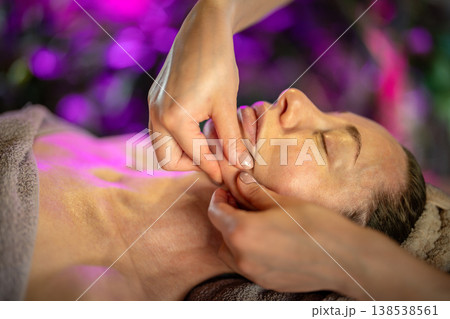 Relaxed woman receiving facial massage from professional cosmetologist in luxury spa clinic. Relaxed woman receiving facial massage from professional cosmetologist in luxury spa clinic. 138538561