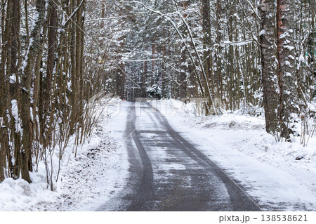 Countryside roadway surrounded by trees forest covered in snow on cold winter day. Countryside roadway surrounded by trees forest covered in snow on cold winter day. 138538621