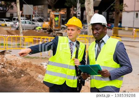 Young worker is discussing a project with a colleague, showing him something Young worker is discussing a project with a colleague, showing him something 138539208