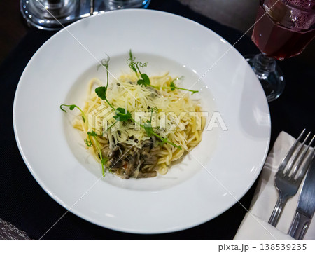 Pasta with portobello mushrooms in creamy sauce, cheese, greens 138539235