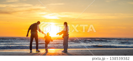 Family enjoying vacation walking on beach at sunset 138539382