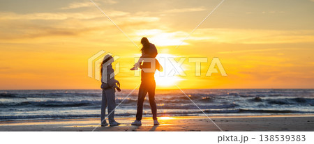Family enjoying sunset together on ocean beach 138539383