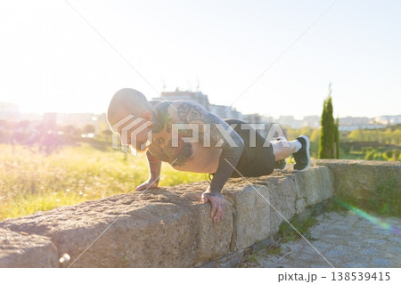 Tattooed man doing push-ups showing strength outdoor 138539415
