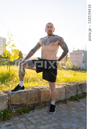 Tattooed man standing confidently in urban park 138539416