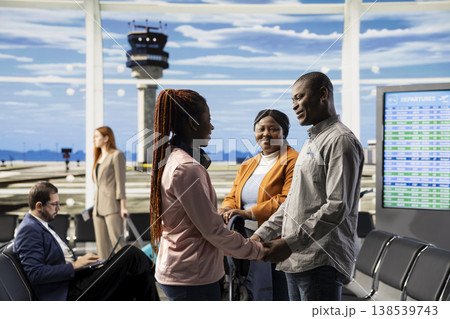 Teenager traveling alone, father hugging as goodbye, airport terminal lounge, daughter boarding the plane and flying abroad leaving single parent behind. African american small family. 138539743