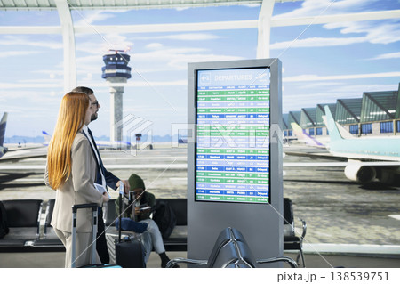 Woman business consultant checking flight information on screen in airport, preparing for business trip departure in busy terminal waiting area. Travelers near the boarding gate. Woman business consultant checking flight information on screen in airport, preparing for business trip departure in busy terminal waiting area. Travelers near the boarding gate. 138539751