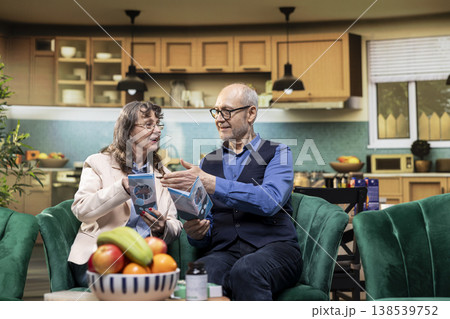 Retired couple reading flyer with medical recommendations for wellness, checking medicaments information for recovery. In-home healthcare routine focus on healthy lifestyle choices. 138539752
