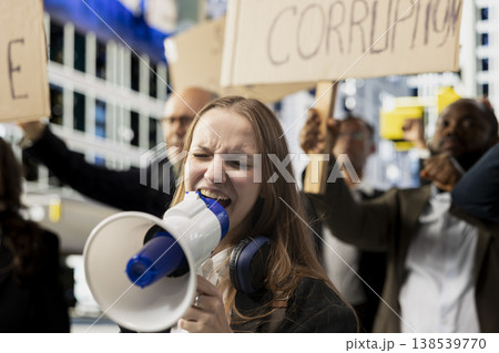Gen z young adult with loudspeaker attends political rally marching against corruption and bad governing, raising signs for equality and anti-censorship. Awareness through serious political activism. Gen z young adult with loudspeaker attends political rally marching against corruption and bad governing, raising signs for equality and anti-censorship. Awareness through serious political activism. 138539770