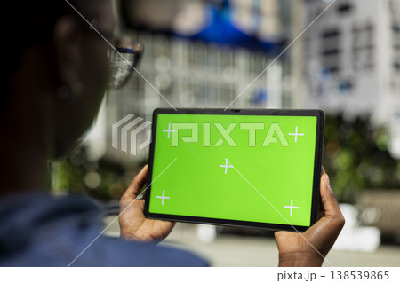 Woman using isolated screen tablet in city, relaxing by looking at social media posts on touchscreen display. Girl using mockup device to browse internet content, urban landscape background, close up 138539865