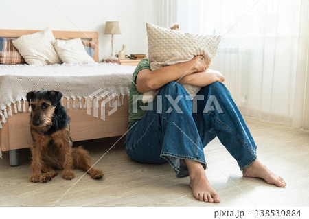 Sad woman covering face with a pillow, experiencing depression, stress, and anxiety in the bedroom, with a worried dog Sad woman covering face with a pillow, experiencing depression, stress, and anxiety in the bedroom, with a worried dog 138539884