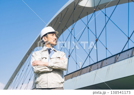橋の前で遠くを眺める男性作業員 138541173