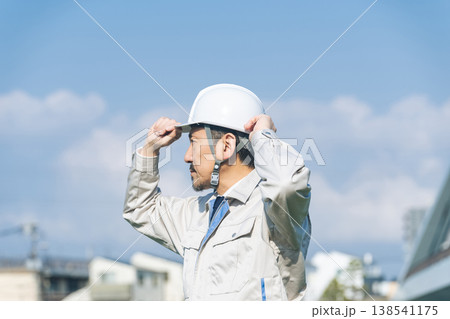 都市の前で遠くを眺める男性作業員 都市の前で遠くを眺める男性作業員 138541175