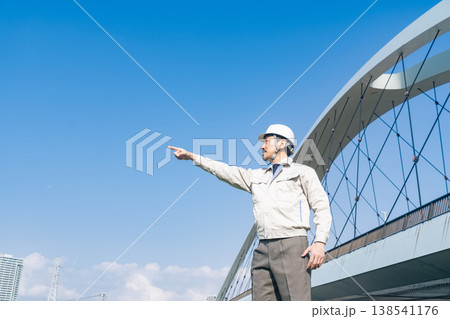 橋の前で遠くを眺める男性作業員 138541176