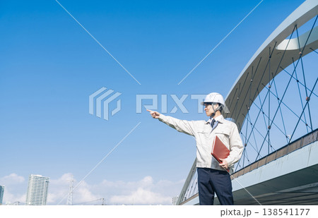 橋の前で遠くを眺める男性作業員 138541177