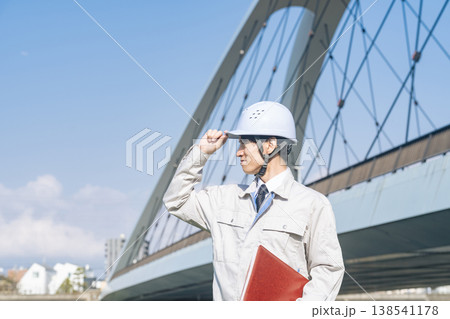 橋の前で遠くを眺める男性作業員 138541178