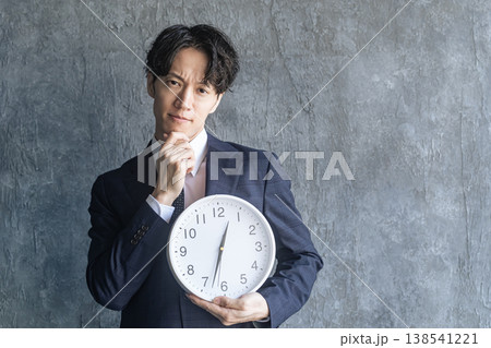 時計を持って悩む若い男性ビジネスパーソン 時計を持って悩む若い男性ビジネスパーソン 138541221