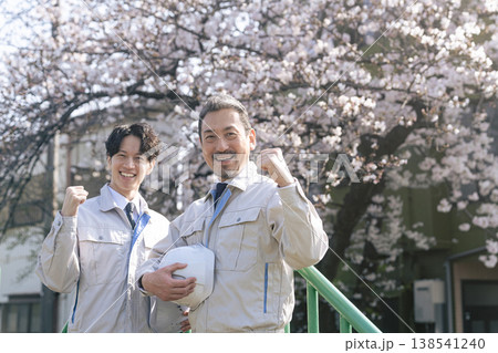 桜の前でガッツポーズする男性作業員のグループ 138541240