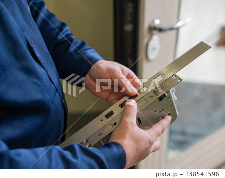 The technician installs a smart electronic lock on the front door. 138541596