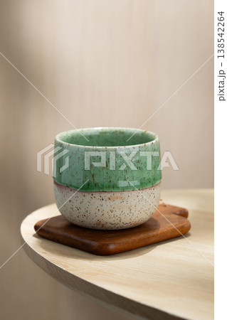 Japanese Style Ceramic Tea Cup on Wooden Coaster with Soft Natural Light 138542264