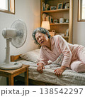 扇風機のある部屋で寝苦しそうにするシニア高齢女性 138542297